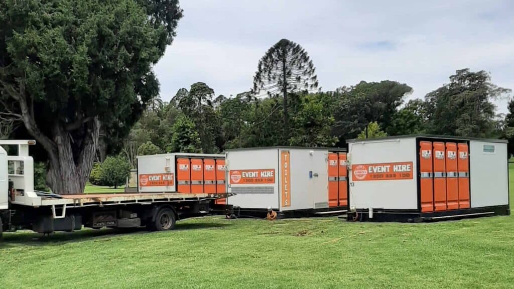 three blocks of multiple portable toilets being loaded off by a transportation truck