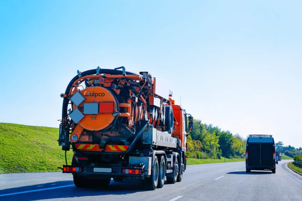 A Quipco vacuum waste truck driving on a highway
